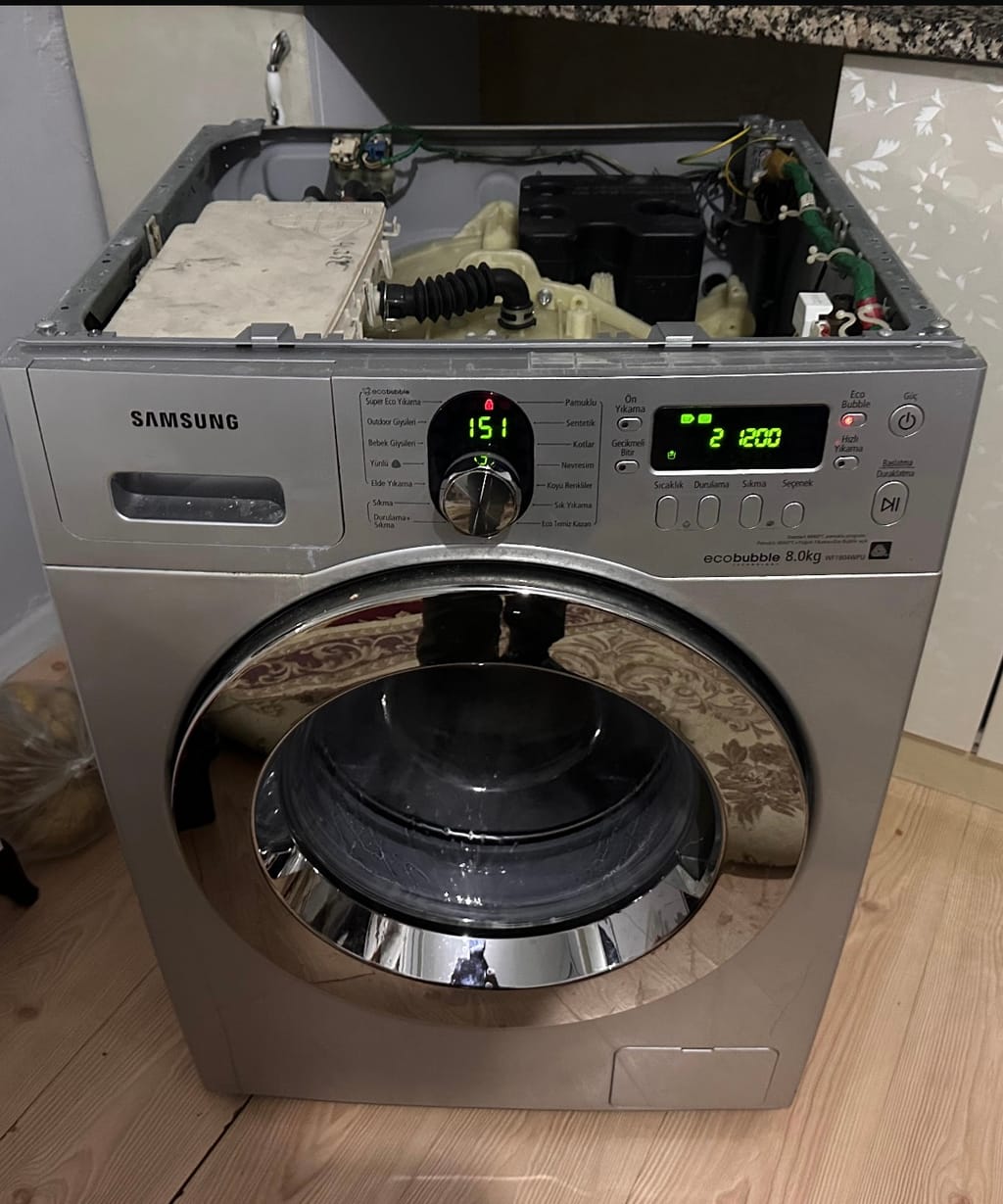 Üst kapağı açılmış Samsung çamaşır makinesi, elektronik kartı görünür halde